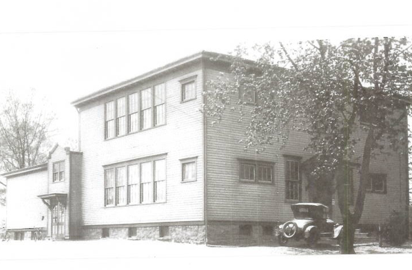 A Black and White Image of a House With a Car