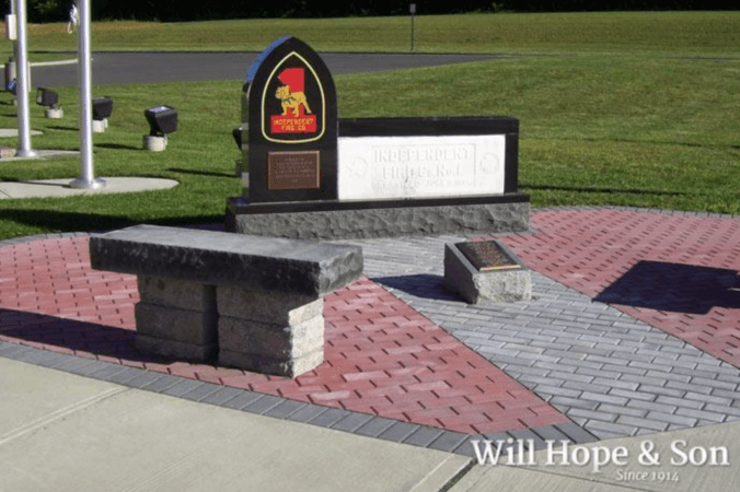 A Stone Bench With Black Plaque With Logo